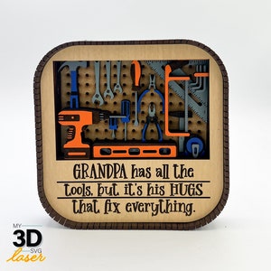 May include: A wooden sign with a tool-themed design. The sign features a pegboard with various tools, including a drill, a level, and spanners. The text on the sign reads "GRANDPA has all the tools, but it's his HUGS that fix everything."
