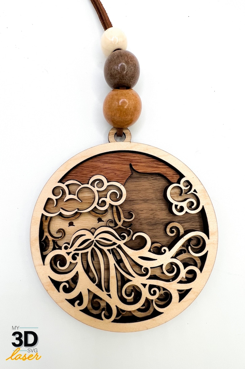 May include: A wooden ornament with a detailed design of a face with a beard and clouds. The ornament is brown and has a light brown cord with wooden beads.