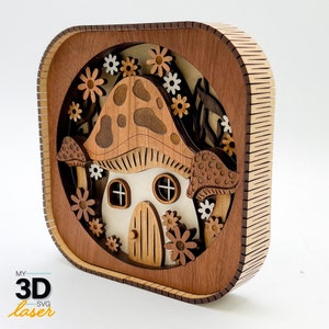 以下が含まれることがあります： 白いドアと窓が付いたキノコの家をモチーフにした、木製の3Dレーザーカットモデル。家は花と葉に囲まれています