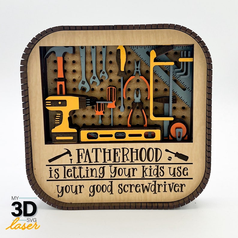 May include: A wooden sign with a brown frame and a pegboard design. The pegboard is filled with various tools, including a drill, screwdrivers, pliers, and a spirit level. The sign reads "Fatherhood is letting your kids use your good screwdriver."