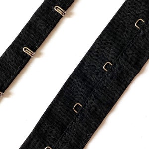 May include: Black fabric bra strap with silver hook and eye closures.