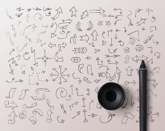 May include: A white surface with a variety of hand-drawn arrows in black ink. A black stylus and a black circular object are also on the surface.