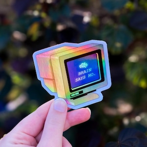 Puede incluir: Una pegatina holográfica de un monitor de ordenador retro. La pantalla muestra un gráfico de un cerebro y el texto "BRAIN SAYS NO." La pegatina tiene un efecto iridiscente de arcoíris, con colores que cambian de amarillo a azul.