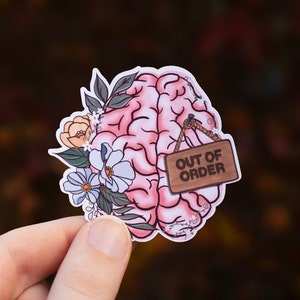 May include: A pink brain with floral details and a wooden sign that reads "OUT OF ORDER" hanging from it.