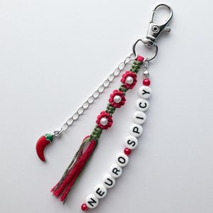 May include: Red and green keychain with a red chilli pepper charm and a beaded word "NEUROSPICY".