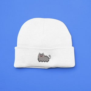 May include: White beanie with a pixelated grey cat design.