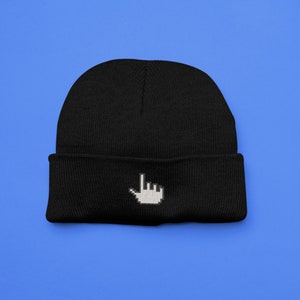 Op de afbeelding: Zwarte beanie met een wit gepixeld handcursorontwerp. De hoed is gemaakt van een zacht gebreid materiaal en heeft een omgeslagen rand. Het ontwerp is gecentreerd op de voorkant van de hoed.