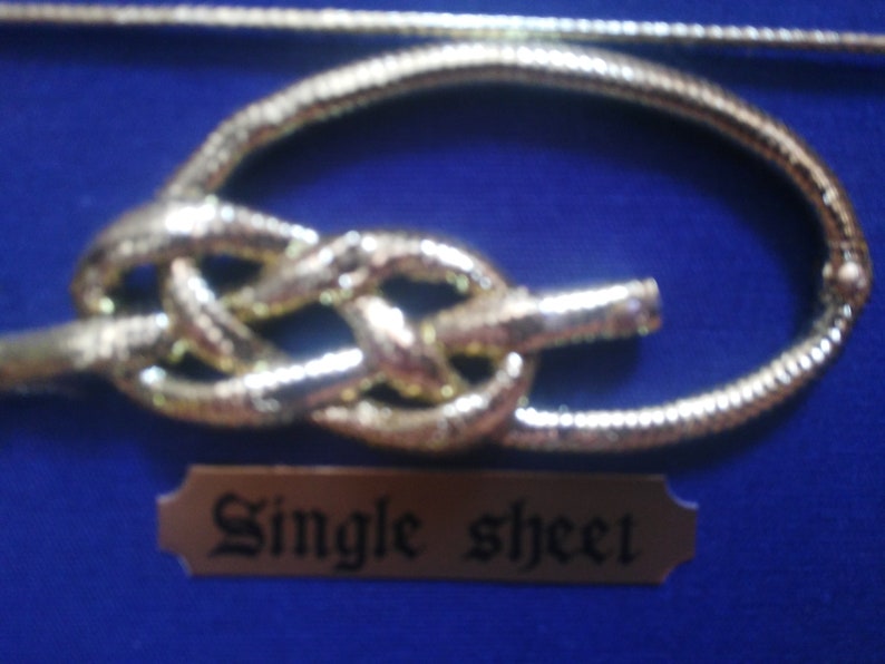 Detail of knot made of golden rope, fabric background and golden cardboard label