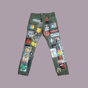 May include: Green cargo pants with various patches and graphics, including "Cartoon Network", "Make a Hero", and "Morgue".