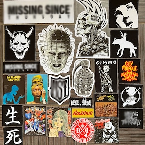 Puede incluir: Una colección de pegatinas con varios diseños, incluyendo una calavera con un mohawk, una máscara de demonio, un personaje de la película "Hellraiser", una calavera con una bomba, un personaje de la película "Gummo", un logotipo de morgue de la ciudad, un personaje japonés, un personaje de manga y un logotipo de diamante.