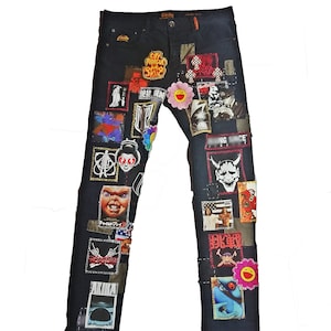 Peut inclure: Un jean en denim noir avec une variété de patchs colorés cousus dessus. Les patchs présentent des images de personnages de dessins animés, de fleurs et du texte.