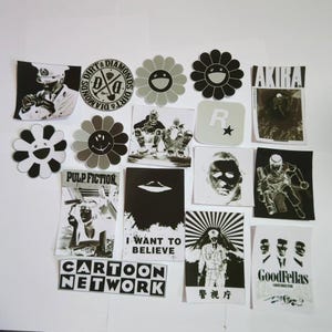 Pode incluir: Uma coleção de adesivos preto e branco com vários designs, incluindo uma flor com um rosto sorridente, um logotipo com o texto "Dirt & Diamonds", um personagem de desenho animado, um OVNI, um rosto, um texto que diz "I Want to Believe", um logotipo da Cartoon Network, um texto que diz "Pulp Fiction", um texto que diz "Akira", um texto que diz "Goodfellas", um texto que diz "R", e um texto que diz "警視庁".