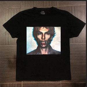 May include: Black t-shirt with a graphic print of a man's face with a blue and white background. The text "Casual Outfit" is printed on the tag.
