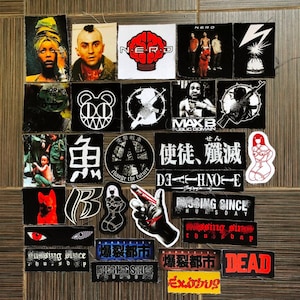 Könnte beinhalten: Eine Sammlung bunter Aufkleber mit verschiedenen Designs, darunter ein Schädel, ein Blitz, ein Gehirn, eine Comicfigur und die Wörter "NERD", "Missing Since Thursday" und "Dead".