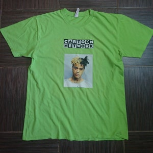 May include: A green t-shirt with a black and white image of a man with dreadlocks. The text "CARTOON NETWORK" is printed in black on a white background above the image.