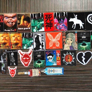 Puede incluir: Una colección de pegatinas coloridas con varios personajes, diseños y textos. Las pegatinas incluyen imágenes de una calavera, una mariposa, un corazón, un demonio y un robot. El texto en las pegatinas incluye "AKIRA", "Missing Since", "Gummo", "Child's Play 3" y "Death God".