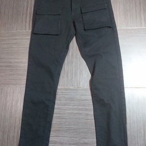 May include: Black cargo pants with zippered hems and large pockets on the front. The pants have the text "Black Scale" and "Made in USA" on the back waistband.