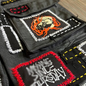 May include: Black denim pants with multiple patches sewn on. The patches are black, white, red, and yellow. One patch has a white graphic that says "Missing Since Thursday".