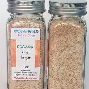 Può includere: Due barattoli di vetro con coperchi argentati pieni di una miscela di zucchero di chai marrone chiaro. L'etichetta riporta "INSTA-FUSE" Zucchero aromatizzato, "ORGANIC" Zucchero di chai, 3 oz, Ingredienti: Zucchero di canna puro biologico, Miscela di spezie di chai biologico, OutLawFoodie.etsy.com