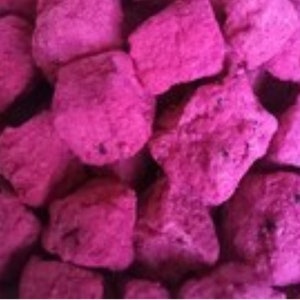 May include: A close-up of a pile of pink dragon fruit candy. The candy is in small, irregular chunks.