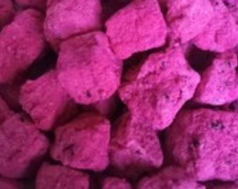 May include: A close-up of a pile of pink dragon fruit candy. The candy is in small, irregular chunks.