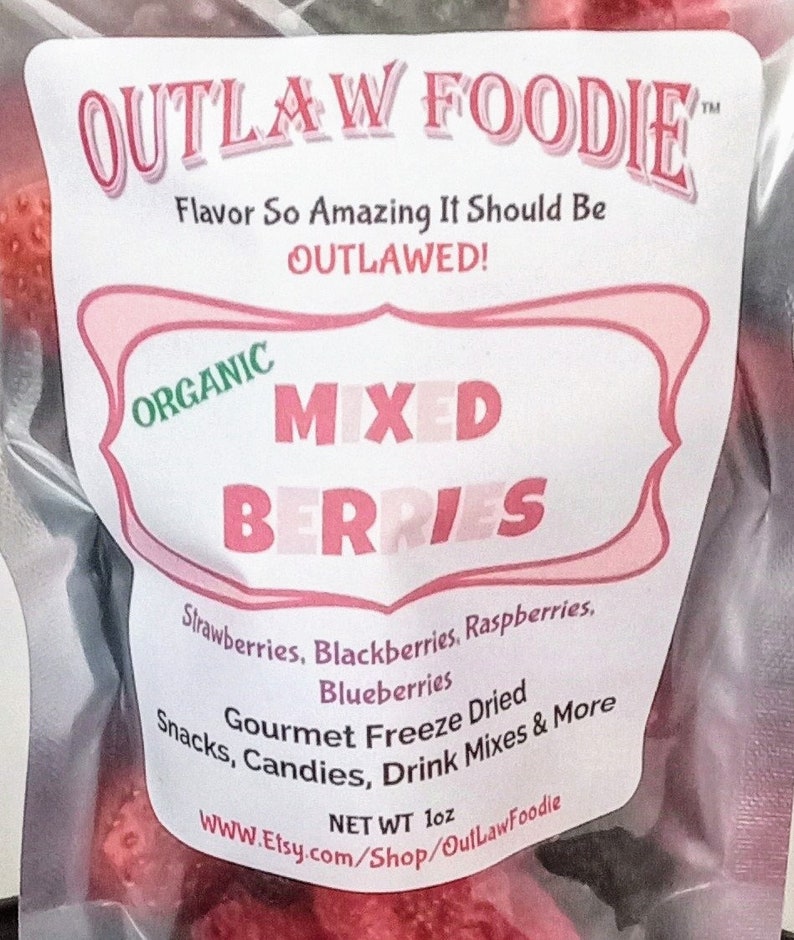 Pu&ograve; includere: Un sacchetto rosa e bianco con un'etichetta che recita "OUTLAW FOODIE" e "ORGANIC MIXED BERRIES". L'etichetta elenca anche gli ingredienti: fragole, more, lamponi, mirtilli. Il sacchetto contiene bacche liofilizzate e ha un peso netto di 1 oz.