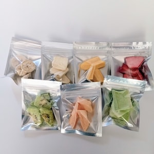 May include: Assortment of freeze-dried fruit pieces in clear, silver-sealed bags. The selection includes banana slices, white fruit chunks, orange-yellow pieces, red fruit slices, green kiwi slices, peach-colored pieces, and green fruit pieces.