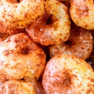 May include: Close-up of a pile of golden brown donuts covered in cinnamon sugar.