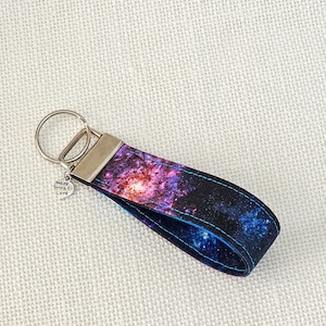 May include: A galaxy-themed key chain with a silver key ring and a charm that says "made with love".