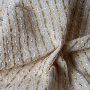 May include: White fabric with gold stripes. The fabric is textured and has a subtle sheen.