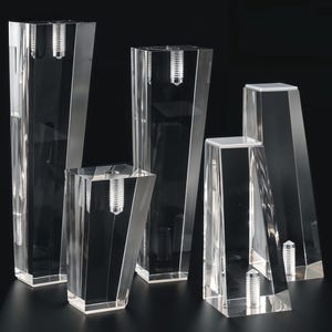 May include: Five clear acrylic furniture legs with a beveled edge and a screw hole at the top. The legs are different sizes and shapes.