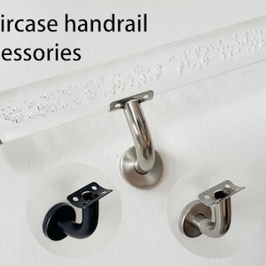 Puede incluir: Accesorios para barandilla de escalera. Una barandilla de acrílico transparente con acabado plateado y superficie texturizada. Se muestran tres soportes de barandilla diferentes: uno plateado, uno negro y uno plateado con borde redondeado.