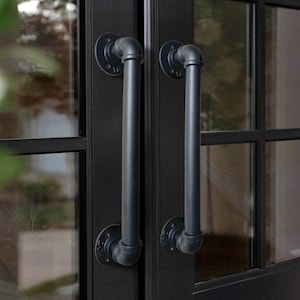 May include: A pair of black industrial pipe door handles with a black finish. The handles are mounted on a black door with glass panels.