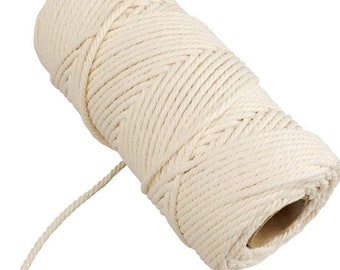 May include: A roll of natural white cotton twine, perfect for crafting, wrapping, or decorating. The twine is wound around a cardboard tube and a length of twine is hanging off the roll.
