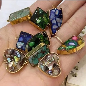 May include: Assortment of colorful resin charms with gold-toned metal frames. The charms feature various shapes, including hearts, squares, and rectangles. The resin is filled with iridescent shell pieces and other decorative elements.