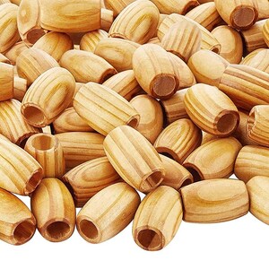 May include: A pile of natural wood beads with a smooth, oval shape and a hole through the center. The beads are light brown with visible wood grain.