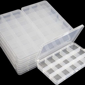 May include: A set of eight clear plastic storage boxes with lids. Each box has 16 compartments. The boxes are stacked on top of each other.