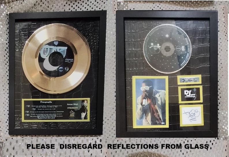 May include: Two framed music memorabilia pieces. One features a gold record with a black and white label. The other includes a CD, a photo of a performer, and other small framed items. Both are in black frames.