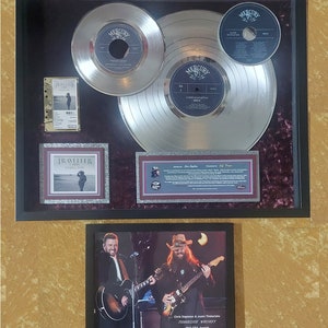 May include: A framed display of two platinum records for Chris Stapleton's album "Traveller". The records are surrounded by a burgundy velvet mat and a smaller framed photo of Stapleton and Justin Timberlake performing together at the 2015 CMA Awards.