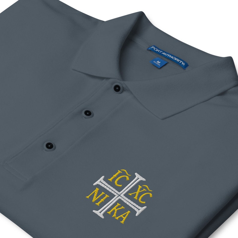 May include: A dark blue polo shirt with a white embroidered cross and the text "IC XC NIKA" in gold.