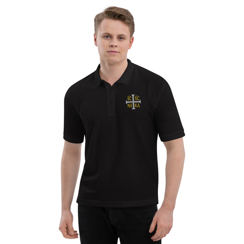May include: Black polo shirt with a silver cross embroidered on the chest. The cross has the words "IC XC NIKA" in gold lettering.