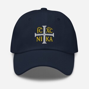 May include: A navy blue baseball cap with a white embroidered cross and the text "IC XC NIKA" in gold.