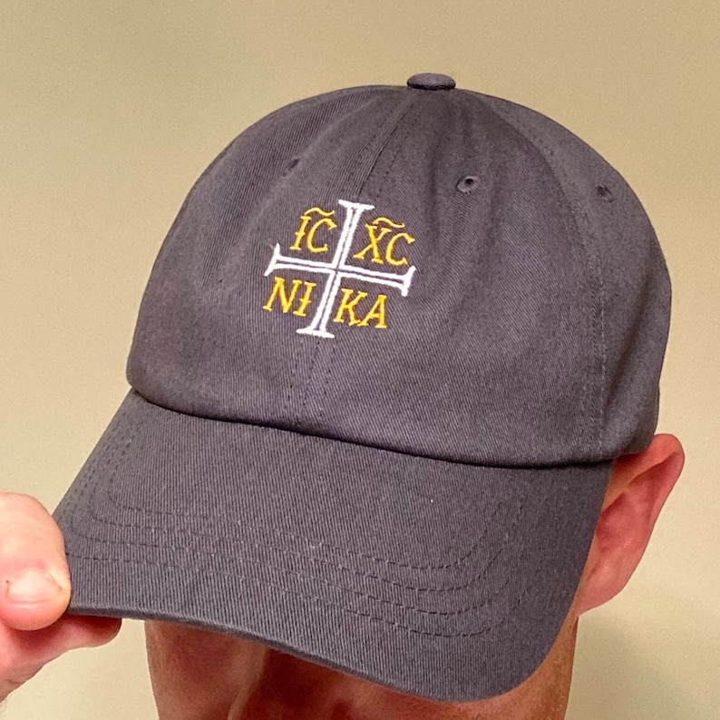 May include: A dark gray baseball cap with a white embroidered cross and the text "IC XC NI KA" in yellow.
