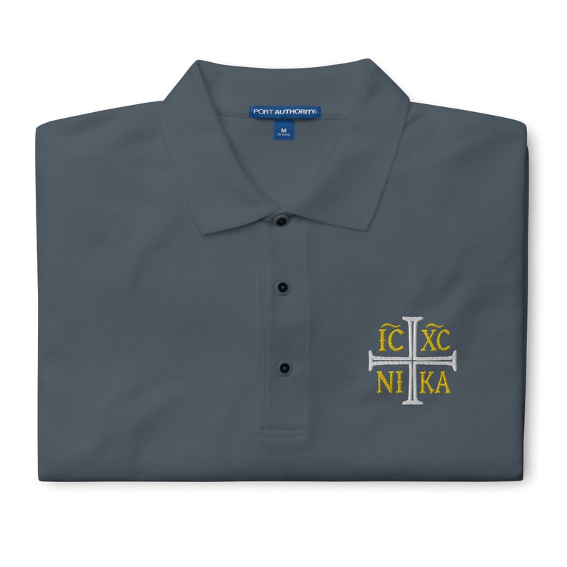 May include: A dark gray polo shirt with a white embroidered cross and the text "IC XC NI KA" in gold lettering.