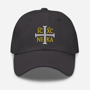 May include: A dark gray baseball cap with a white cross and the text "IC XC NIKA" embroidered in gold.