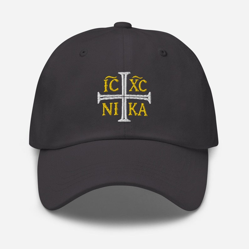 May include: A dark gray baseball cap with a white cross and the text "IC XC NIKA" embroidered in gold.