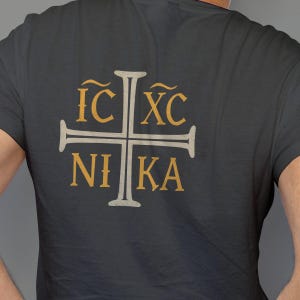 May include: Dark gray t-shirt with a cross design. The cross is white with gold lettering that reads IC XC NIKA. The shirt is made of a soft material.