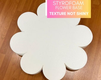 May include: White styrofoam flower base shaped like a flower with 7 petals. The text "STYROFOAM FLOWER BASE TEXTURE NOT SHINY" is printed on a pink and yellow rectangle.