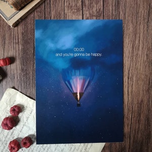 May include: A blue and white hot air balloon with a glowing orange flame ascends into a dark blue night sky with stars. The text "00:00 and you're gonna be happy." is written in white.