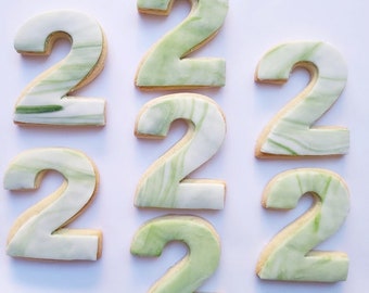 Op de afbeelding: Zeven groene en witte marmerkoekjes in de vorm van het getal twee.